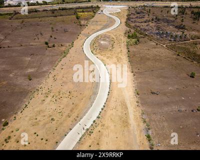 Aerial view of a winding S-shaped road cutting through lush green hills ...