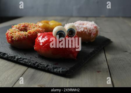 Ponchik donat with eyes on a gray background with space for copyspace text. Preparing for Halloween. Stock Photo