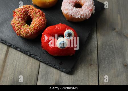 Donat dessert with funny eyes on a gray background with space for copyspace text. Halloween Celebration Concept. Stock Photo