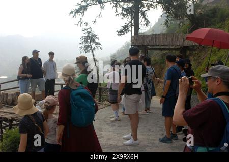 Tourists pose for a photograph with the hazy mountains of Sapa behind ...