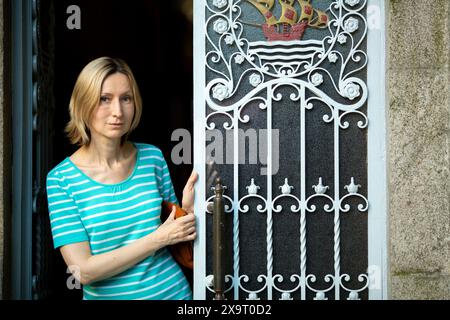 A woman stands in the doorway of a traditional Portuguese home, captured in a close-up shot. Stock Photo
