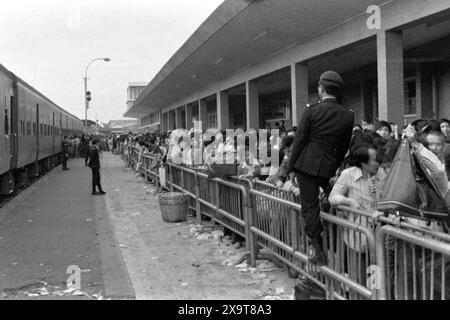 Passengers waiting for a southbound diesel train, Lo Wu Railway Station, Kowloon-Canton Railway, Hong Kong, Lunar New Year 1981. The waiting crowd have all just returned to Hong Kong from mainland China.  Policemen on the platform are engaged in crowd management, due to high holiday-season numbers of passengers. This was before the KCR was electrified in the early 1980s, and the stations and facilities upgraded. Stock Photo