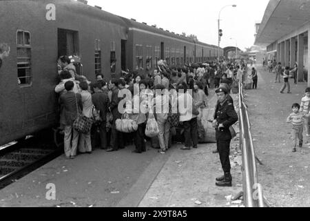 Passengers boarding a southbound diesel train, Lo Wu Railway Station, Kowloon-Canton Railway, Hong Kong, Lunar New Year 1981. The passengers have all just returned to Hong Kong from mainland China.  Policemen on the platform are engaged in crowd management, due to high holiday-season numbers of passengers. This was before the KCR was electrified in the early 1980s, and the stations and facilities upgraded. Stock Photo