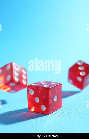 Three red game dices falling on light blue background, closeup Stock Photo