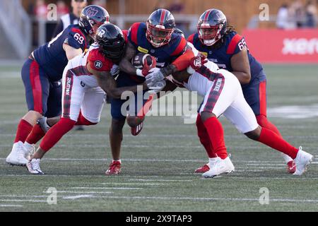 Ottawa, Canada. 31st May, 2024. Montreal Alouettes running back Stevie Scott III (35) carries the ball attempting to break in between Ottawa Redblacks defensive lineman Cleyon Laing (90) and defensive end Lorenzo Mauldin IV (94) during the CFL preseason game between Montreal Alouettes and Ottawa Redblacks held at TD Place Stadium in Ottawa, Canada. Daniel Lea/CSM (Credit Image: © Daniel Lea/Cal Sport Media). Credit: csm/Alamy Live News Stock Photo