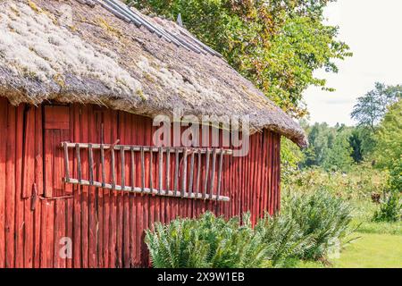 Wooden ladder hanging on the wall on a red barn in the countryside Stock Photo