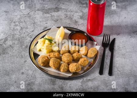 Fried mussels on a metal plate with potato salad on the side. Turkish name: Midye Tava Stock Photo