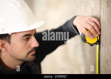 Construction worker using measuring meter on a wall Stock Photo
