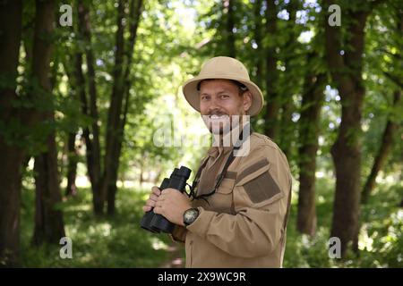 Forester with binoculars examining plants in forest Stock Photo
