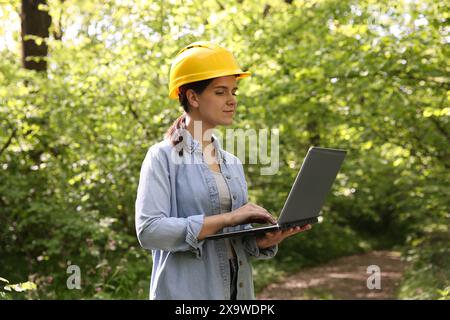 Forester in hard hat with laptop working in forest Stock Photo