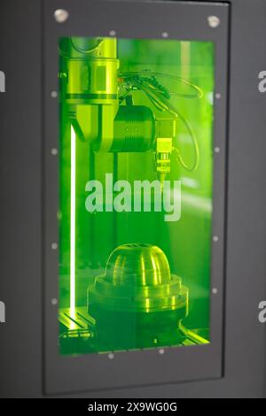 Rotary fiber laser marking CNC machine. Closeup view through green glass safety door. Selective focus. Stock Photo