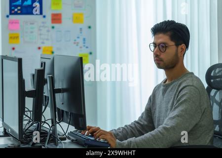 Asian man  prompt engineer develop coding app with software data sitting in front of computer monitor at office Stock Photo
