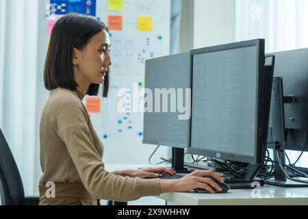 Asian prompt engineer develop coding app with software data sitting in front of computer monitor at office Stock Photo