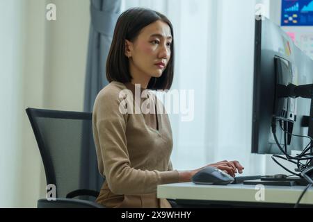 Asian prompt engineer develop coding app with software data sitting in front of computer monitor at office Stock Photo