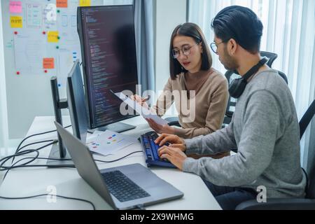 asian and Indian Developer team discussion feedback analysis coding data with software computer at office Stock Photo
