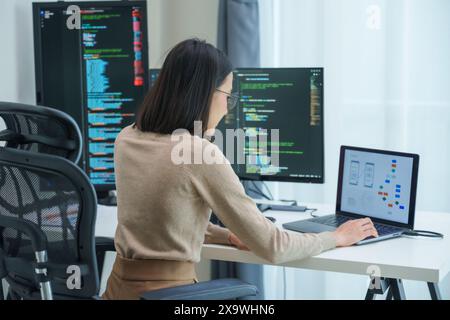 Asian prompt engineer develop coding app with software data sitting in front of computer monitor at office Stock Photo