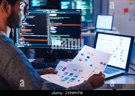 Indian software development working on coding  computer screen and flowchart at night in modern office Stock Photo