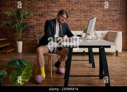 Nerd funny businessman working online on computer in formal suit and funny slippers Stock Photo