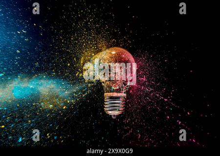 colorful exploding lightbulb powder splash  dark background Stock Photo