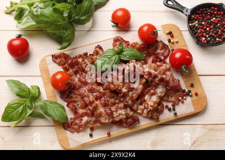 Slices of tasty fried bacon with different spices and tomatoes on wooden table, flat lay Stock Photo