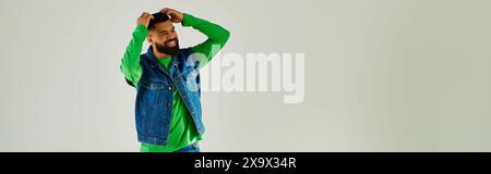 A man with a beard wearing a green long sleeve and blue jeans. Stock Photo