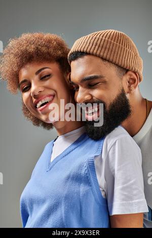 An African American man and woman in stylish clothes laughing together against a grey background. Stock Photo