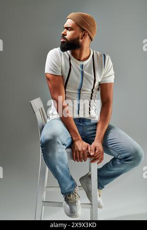 A man with a beard sits thoughtfully on a chair, deep in contemplation, exuding a sense of wisdom and introspection. Stock Photo