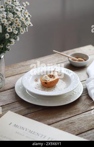 Honey baked pear with ice cream, walnuts, cinnamon, spices with sauce on white plate on wooden table. Stock Photo