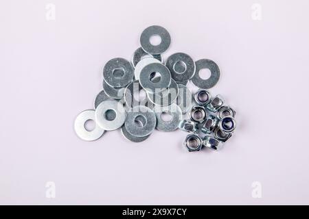 Stack of flat washer and zinc plated hexagon nuts on white background. Stock Photo