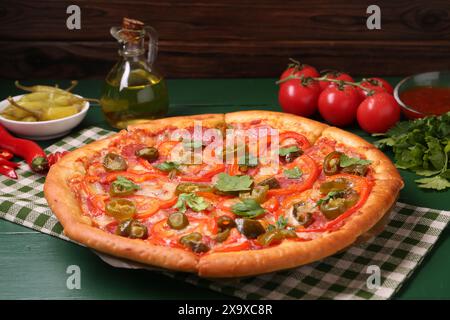 Delicious pizza Diablo and ingredients on green wooden table Stock Photo