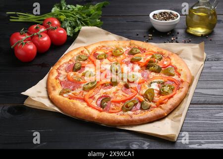 Delicious pizza Diablo and ingredients on black wooden table Stock Photo