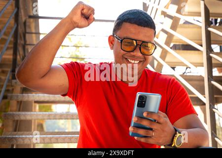 A happy young man wins with an online betting app. Stock Photo