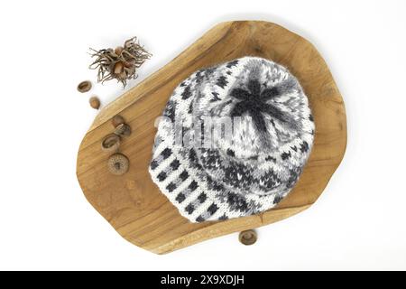 Tabletop photography of a Fair Isle knitted wool hat in white, grey and black shades on a wooden board on a white background Stock Photo