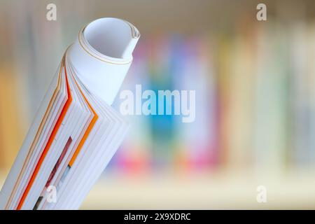 Rolled up magazine, newspaper, information,education,press,journalism concept.blurred bookshelf background,copy space Stock Photo