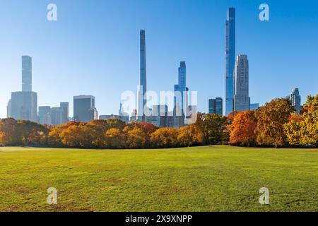 Morning in Central Park Sheep Meadow with lawn and trees. Fall foliage and iconic skyscapers of Billionaires' Row. Manhattan, New York City Stock Photo