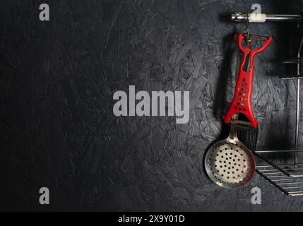 Kitchen utensils on a black wall. Copy space Stock Photo