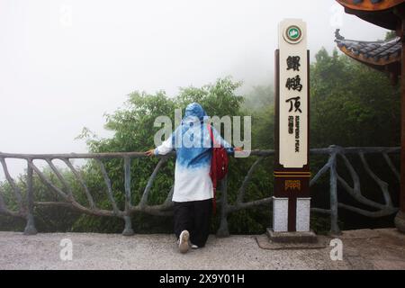 Thai women travelers and chinese people travel visit take photo landscape at cliff viewpoint of Tianmen Mountain National Forest Park while raining mi Stock Photo