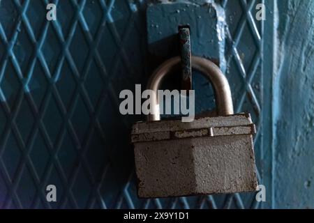 A large lock on the door made of iron painted with blue paint. Stock Photo
