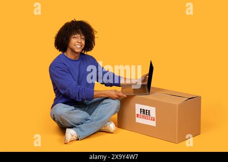 Guy Sitting on Floor With Box and Laptop Stock Photo