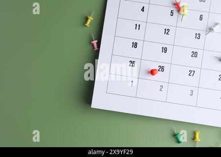 Timetable. Calendar page with drawing pins on green background, top view. Space for text Stock Photo