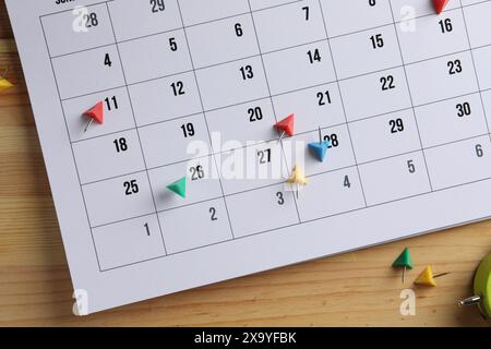 Timetable. Calendar page and drawing pins on wooden table, top view Stock Photo