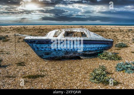 Dark and Moody Abandoned weathered blue boat on Dungeness beach Stock Photo