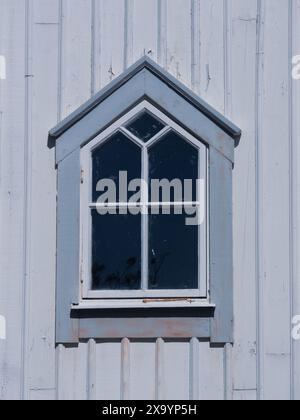 A weathered window on a wooden wall with peeling paint Stock Photo