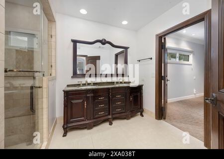 A bathroom with a sink and a large mirror above it in Stock Photo
