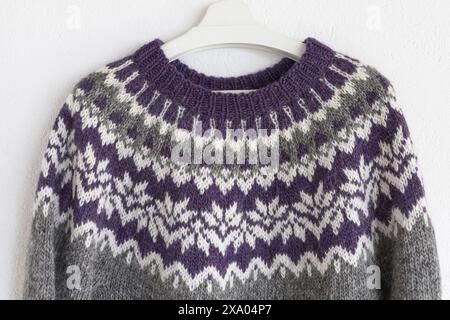 Close-up photo of a large grey, white and violet yoke of a knitted wool lopapeysa sweater in traditional Icelandic knitting pattern Stock Photo