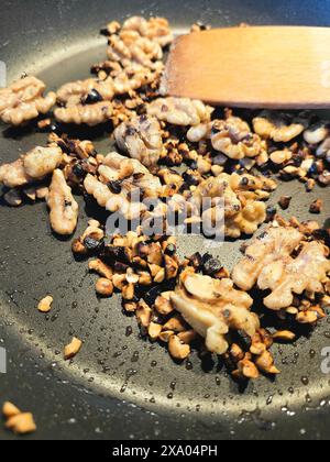 Nuts frying in a pan with a wooden spoon Stock Photo