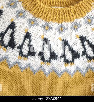 Close-up photography of a yellow white black Icelandic wool knitted kids sweater in Penguin pattern an a yoke and ribbed neckband Stock Photo
