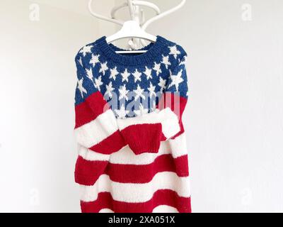 Photo of a USA Flag patriotic knitted wool red blue white sweater with stripes and stars in traditional icelandic pattern with its sleeves tied up han Stock Photo