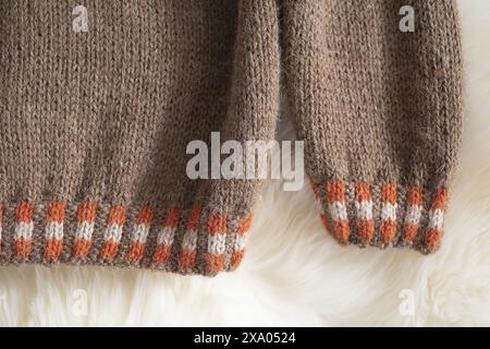Close-up photo of an Icelandic knitted wool lopapeysa sweater in traditional Nordic knitting pattern, details of a brown orange pullover ribbed cuff a Stock Photo
