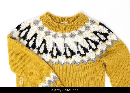 Flat lay photography of a yellow white black Icelandic wool knitted kids sweater in Penguin pattern an a yoke and ribbed neckband on a white backgroun Stock Photo